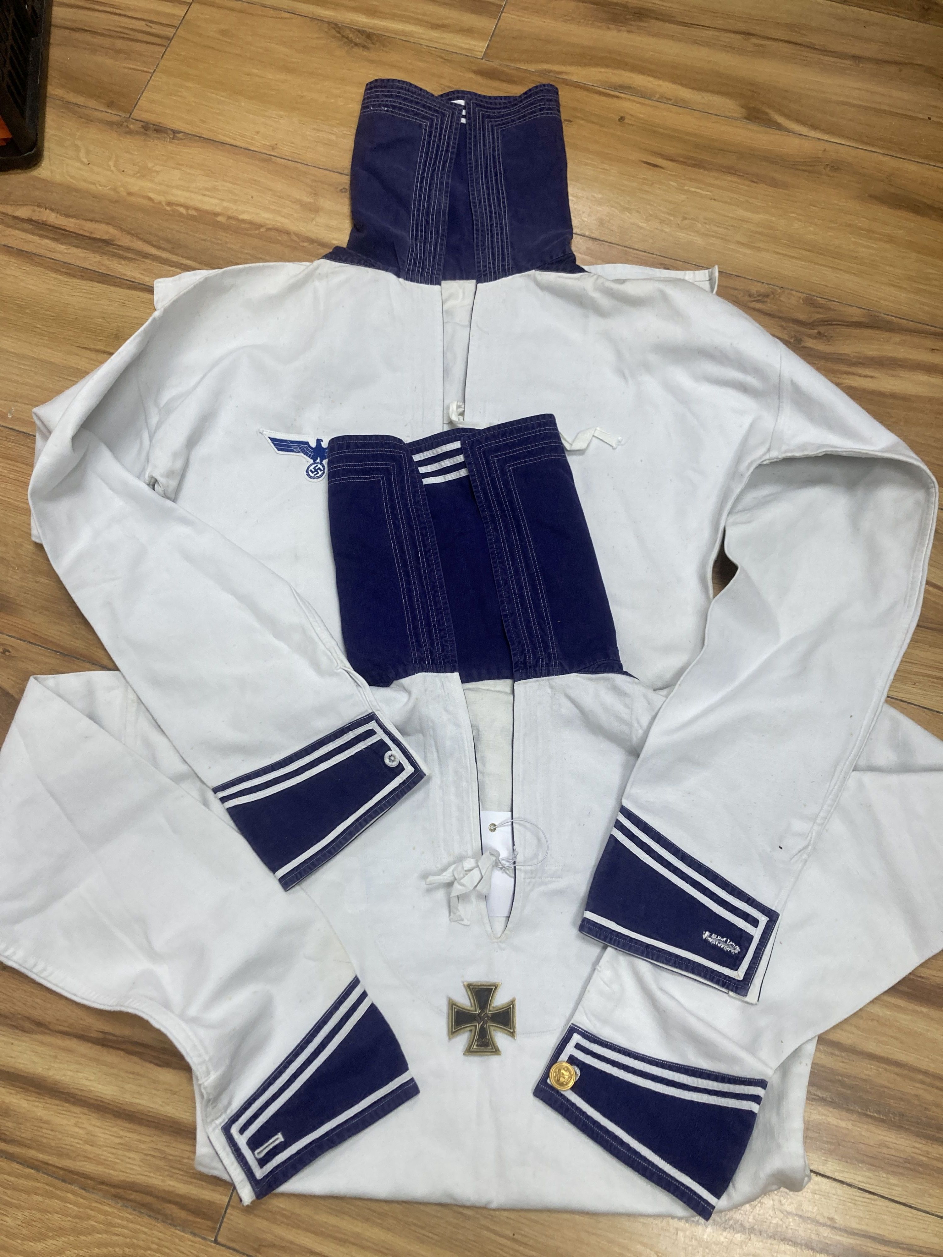 Two German  period white naval tunics, one named 'Schmidt. R, X176 T', together with an associated 1939 iron cross (3)